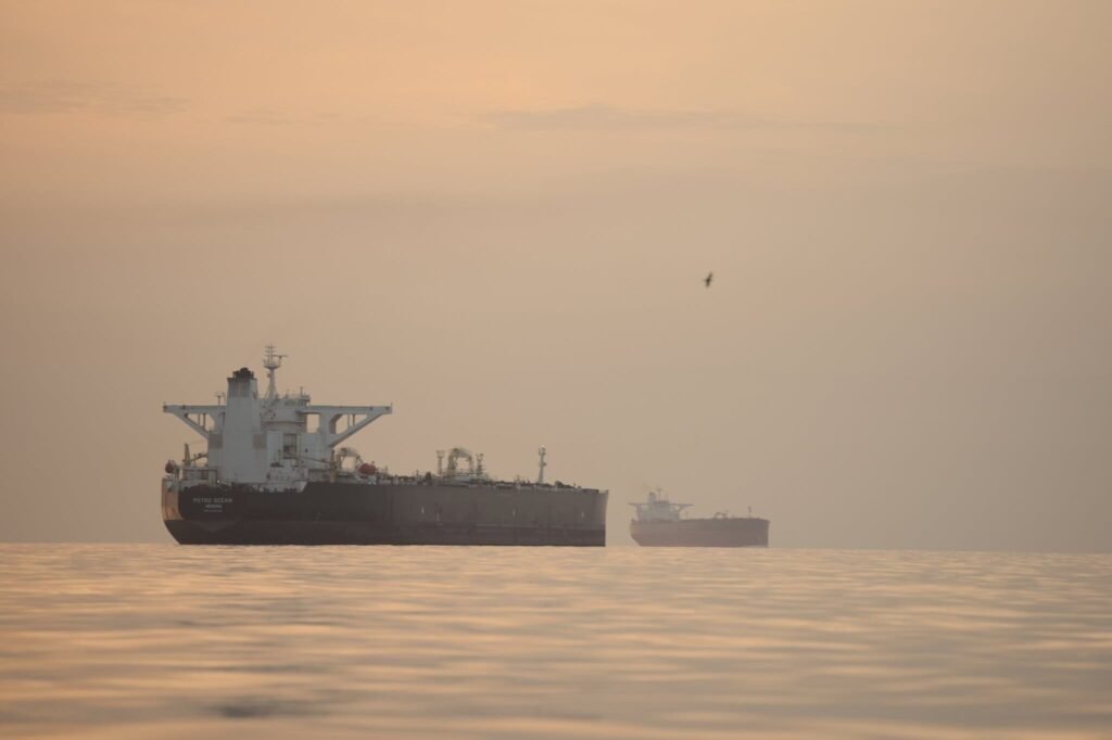 A large cargo ship travels through a narrow strait bordered by coastline.