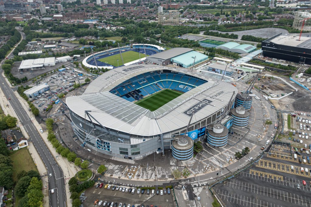 A large modern soccer stadium exterior under a clear sky.