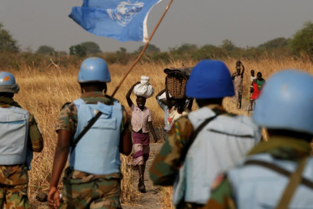 Uniformed United Nations peacekeepers wearing blue helmets standing at a field checkpoint.