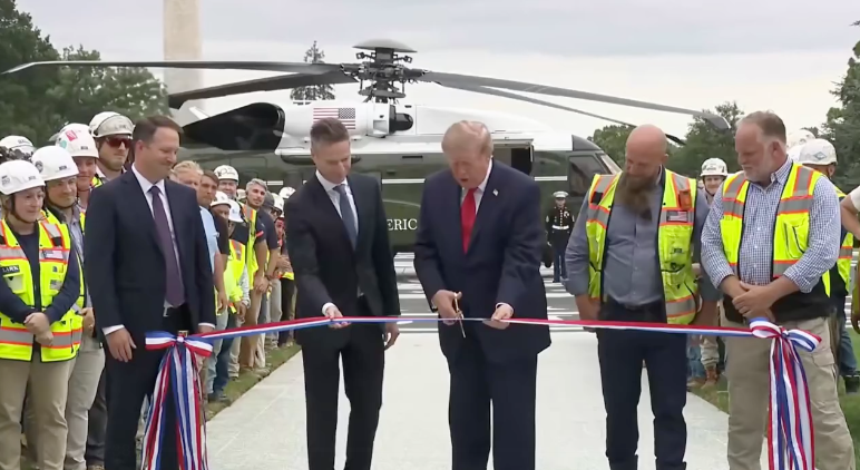 Donald Trump cuts a ceremonial ribbon beside the new White House helipad.