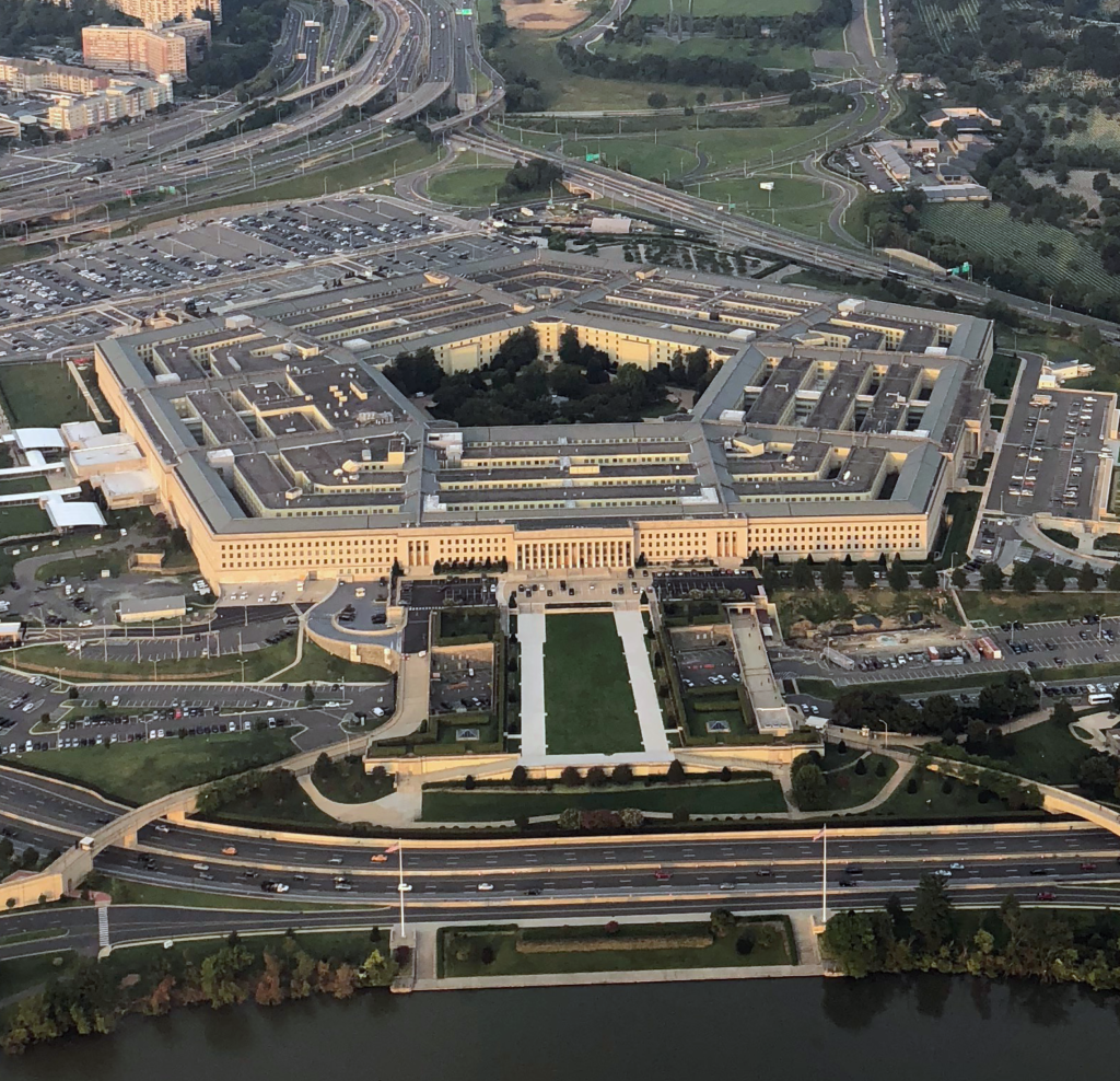 An aerial view of the five-sided Pentagon building surrounded by parking lots and roadways.