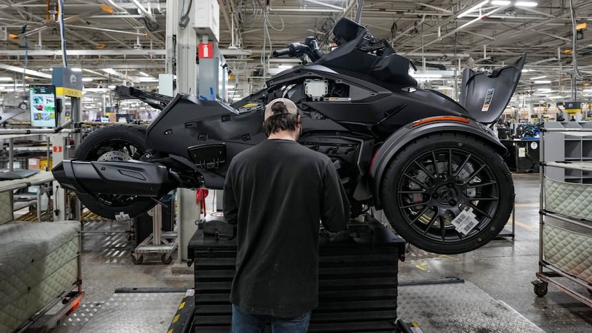 A three-wheeled motorcycle on an assembly line inside a manufacturing facility.
