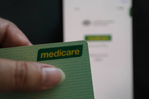 Australian Medicare card beside a computer displaying a government health-services website.