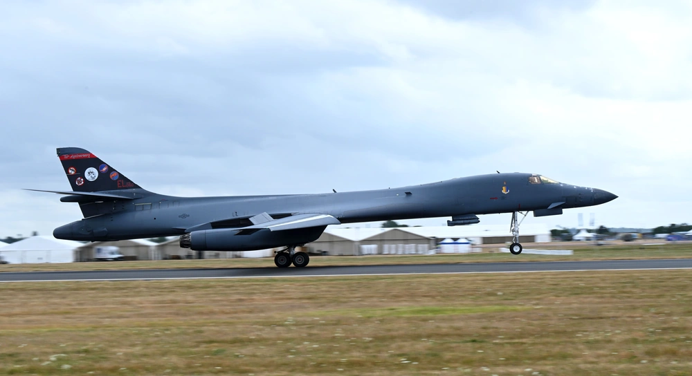 A large gray military bomber parked on an airfield apron under a cloudy sky.