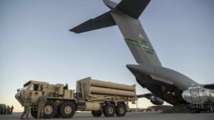 U.S. military personnel load precision-guided munitions onto an aircraft at a military base.