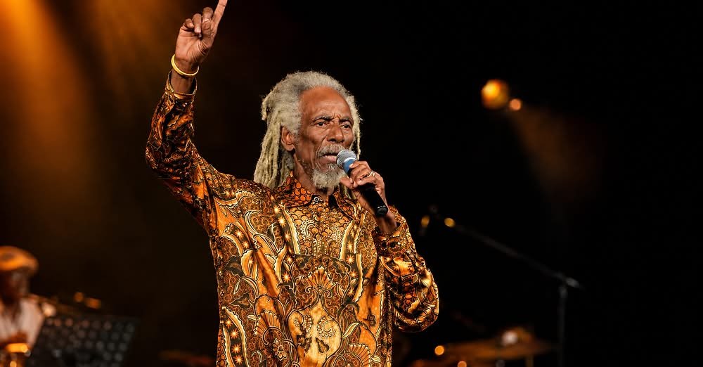 A calypsonian singing into a microphone on a stage.