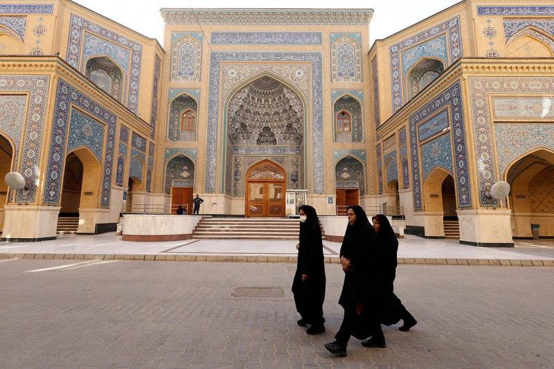 Pilgrims gather outside a golden-domed shrine in a Middle Eastern city.