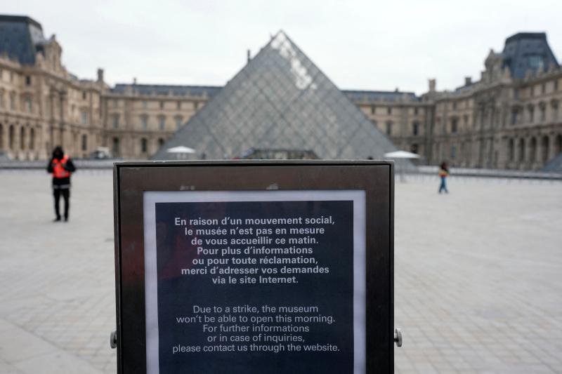 The Louvre pyramid in Paris with few people nearby