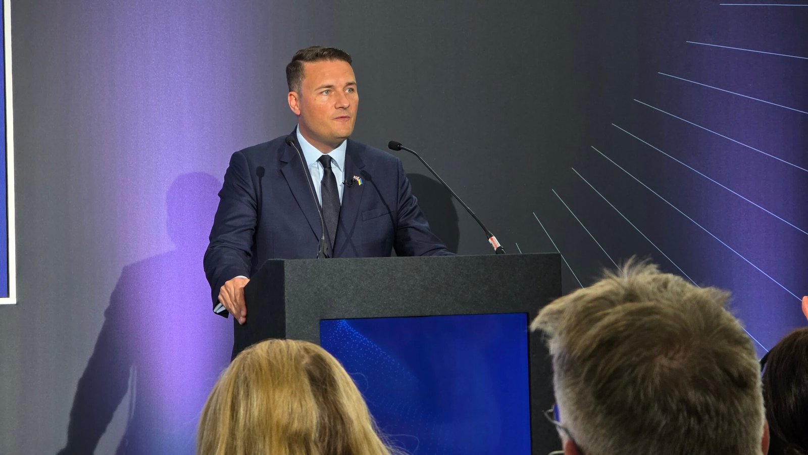 A man in a suit speaking at a podium.