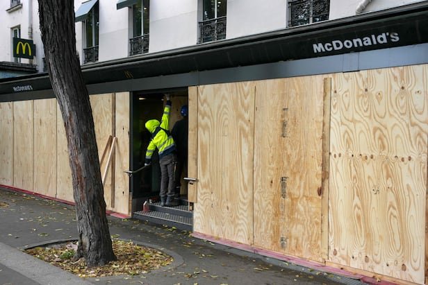 Workers fixing wooden boards over a shop window