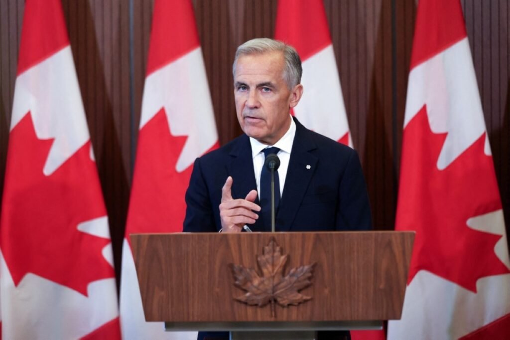 Mark Carney speaking at a podium with Canadian flags behind him.
