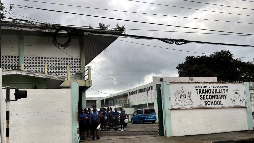 Students in school uniforms walking across a school compound.