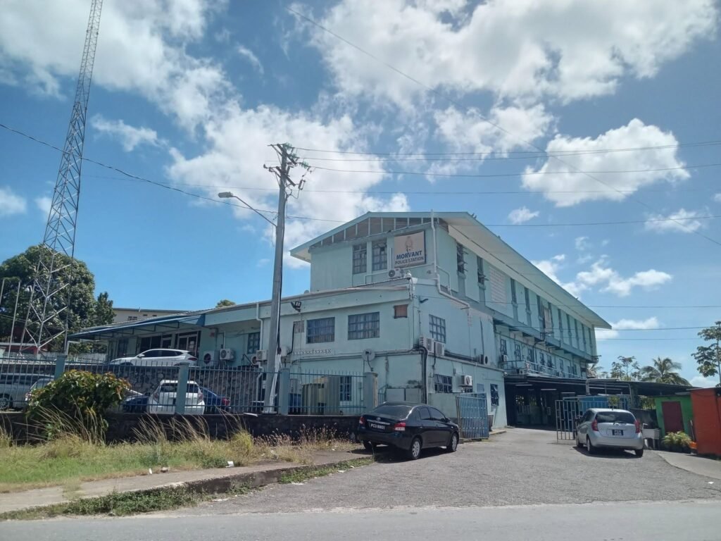 Front entrance of a police station building with a flag and a marked vehicle.