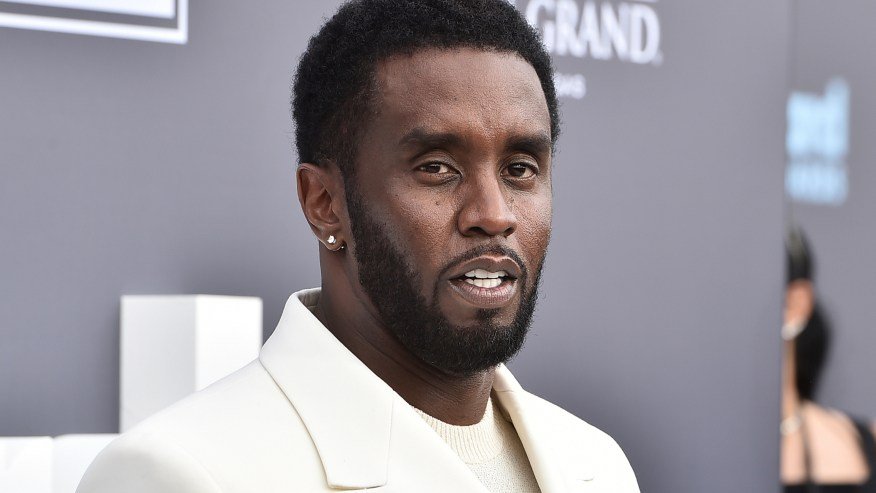 Sean Combs in formal wear posing on a red carpet at an awards show.