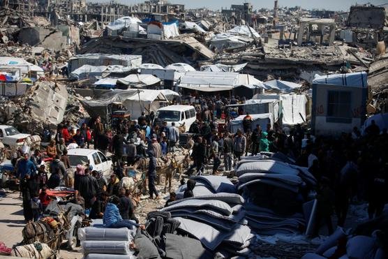 People walk among tents and makeshift shelters in a displacement camp.