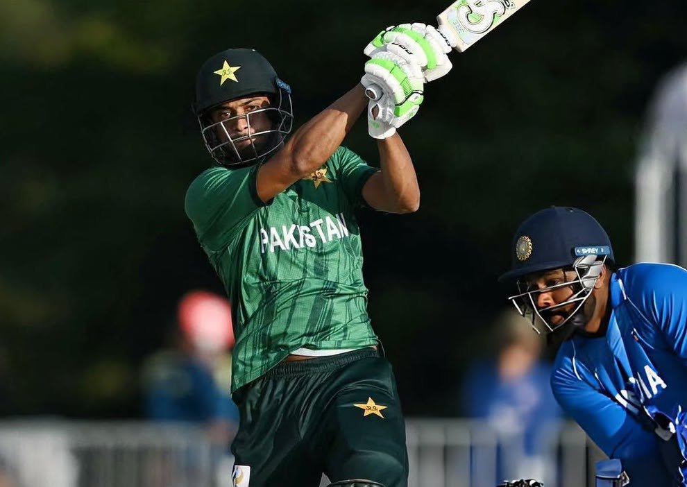 A cricket batsman in a green uniform plays a shot during a match.