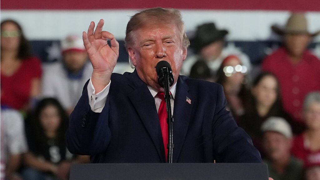Donald Trump speaking at a podium in front of a crowd.
