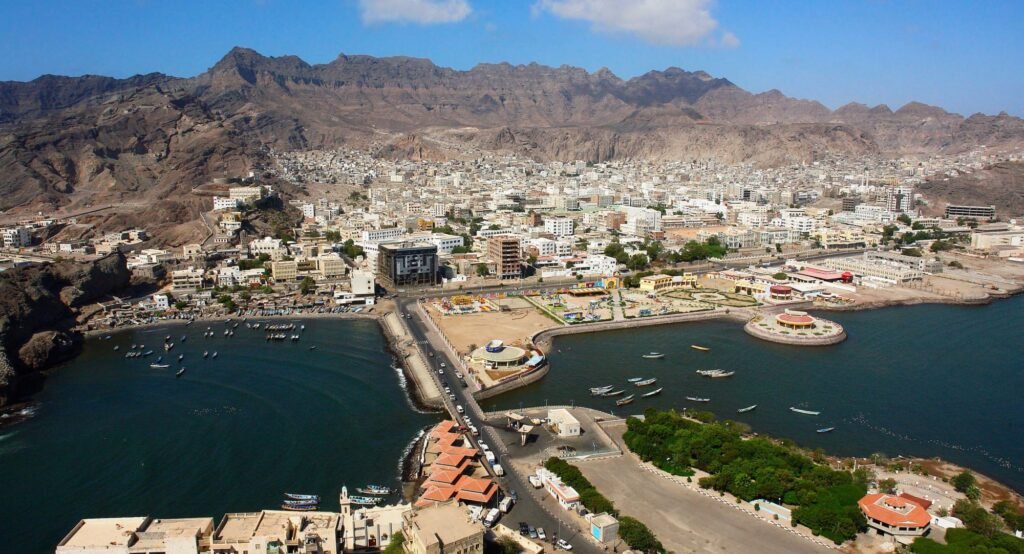 A coastal city with a harbor and buildings along the shoreline at sunrise.