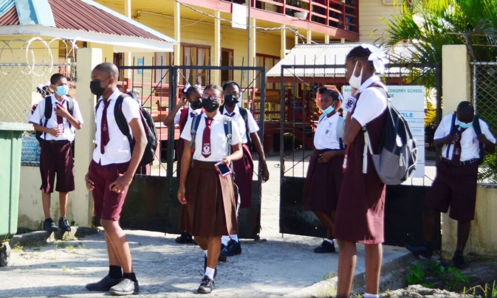 Students in school uniforms walking along a path outside a school building.
