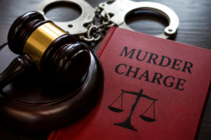 Judge’s gavel, handcuffs and a red book labelled “Murder Charge,” symbolising the murder charges in the Malick double homicide case.