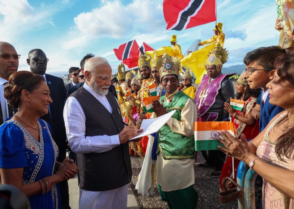 Two heads of government greet each other during an official arrival ceremony, with dignitaries standing behind them.
