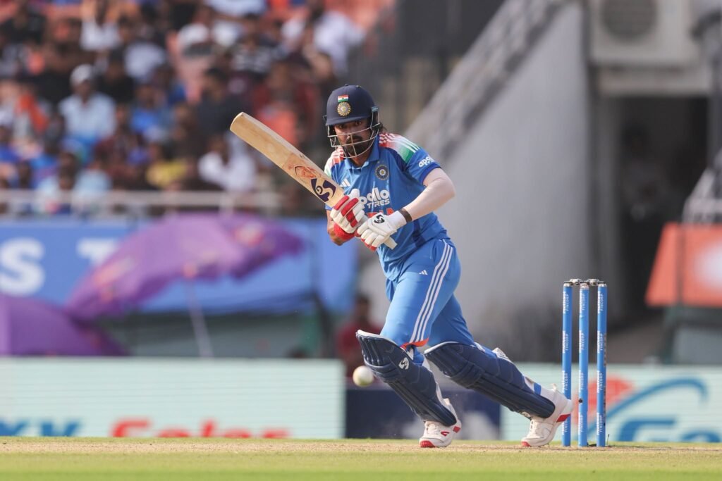 A cricket batsman in a blue India uniform plays a shot during a match.