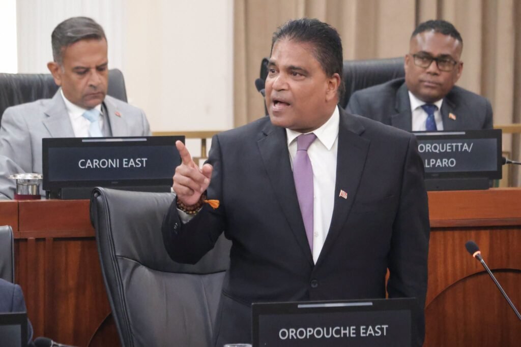 A man in formal attire speaks at a podium during a press briefing.