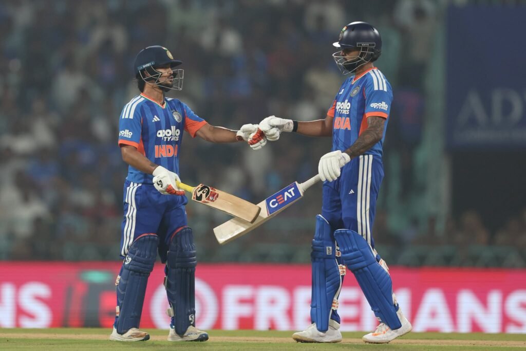 A cricket batsman in a blue uniform plays a shot during a match.