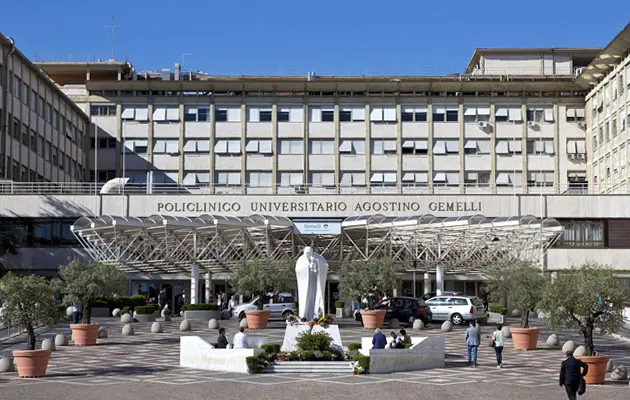 The exterior of a large modern hospital building in Rome with its entrance and signage visible.
