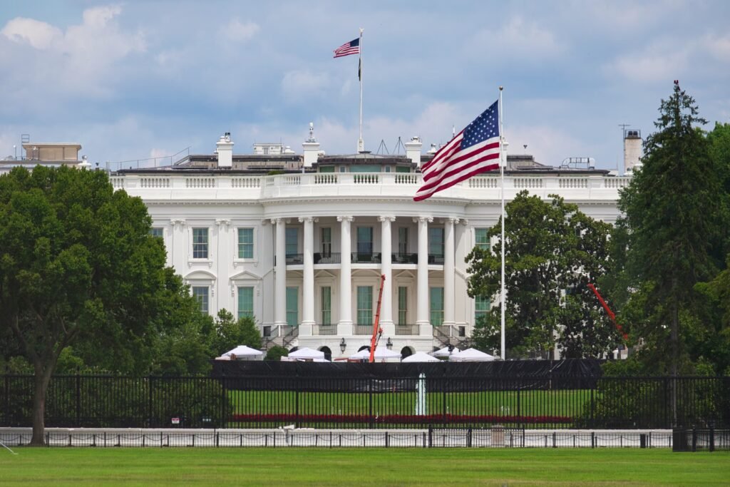 The White House West Wing exterior with the American flag flying on a clear day.