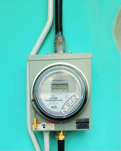 An electricity meter on the outside wall of a house
