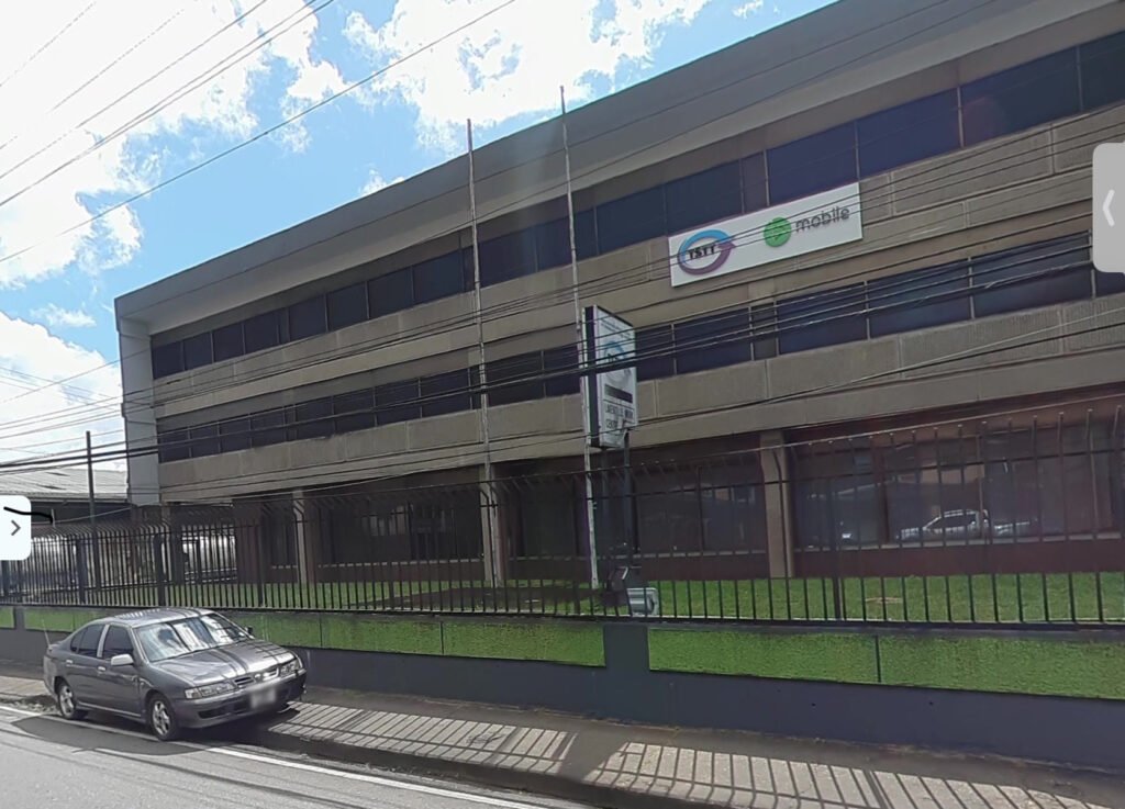 A three-story building with a TSTT and bmobile sign above a fence, with a street sign reading Laventille Work Centre in front.