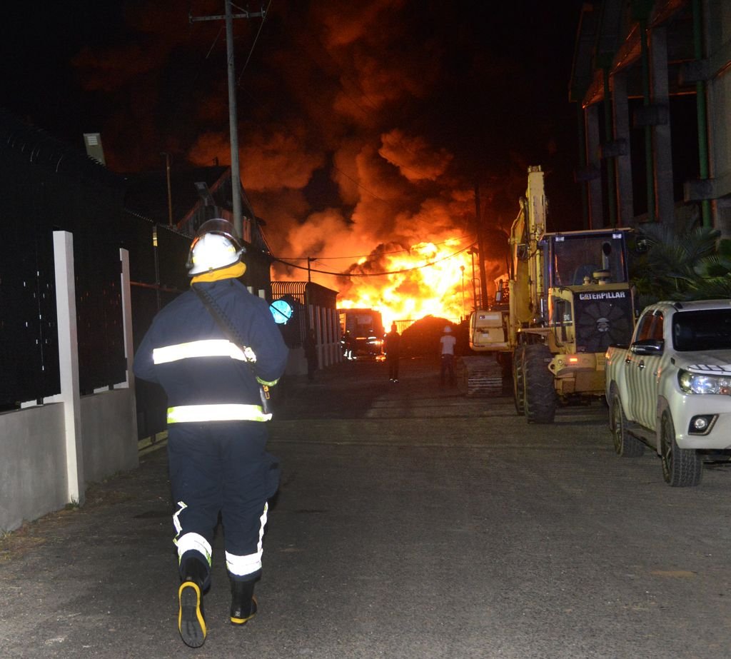 A firefighter in protective gear at the scene of a night fire.