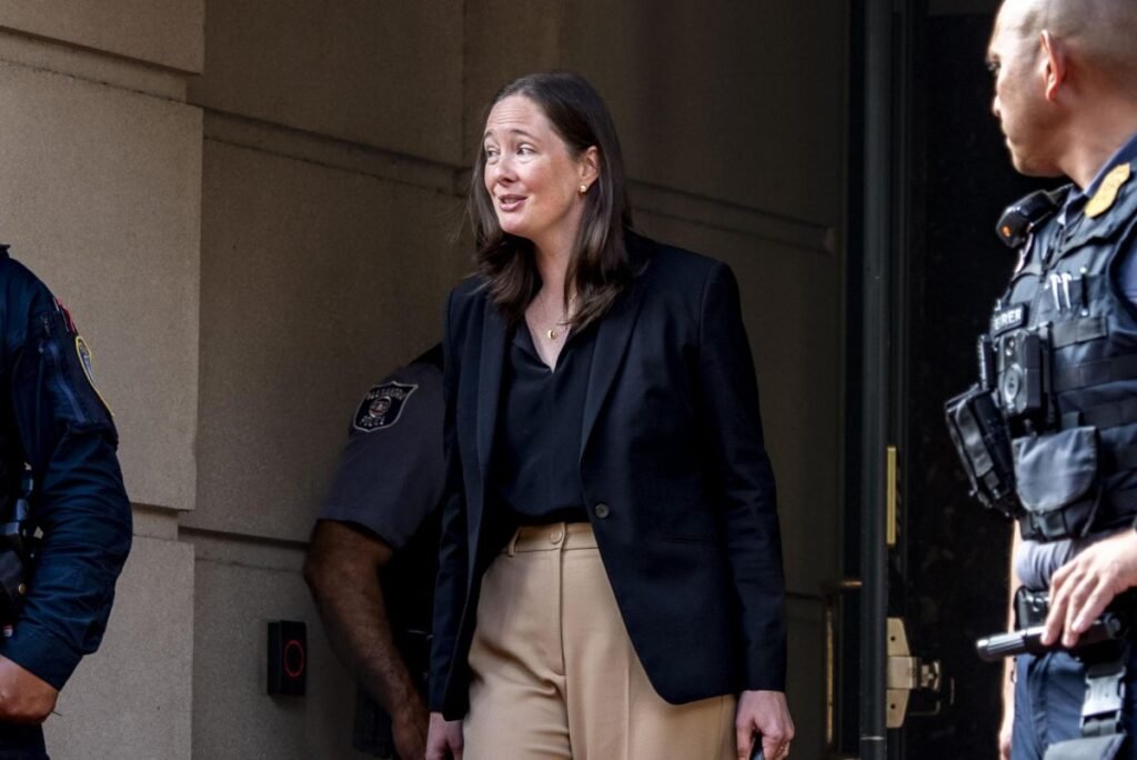 A woman in a dark coat walking down courthouse steps.