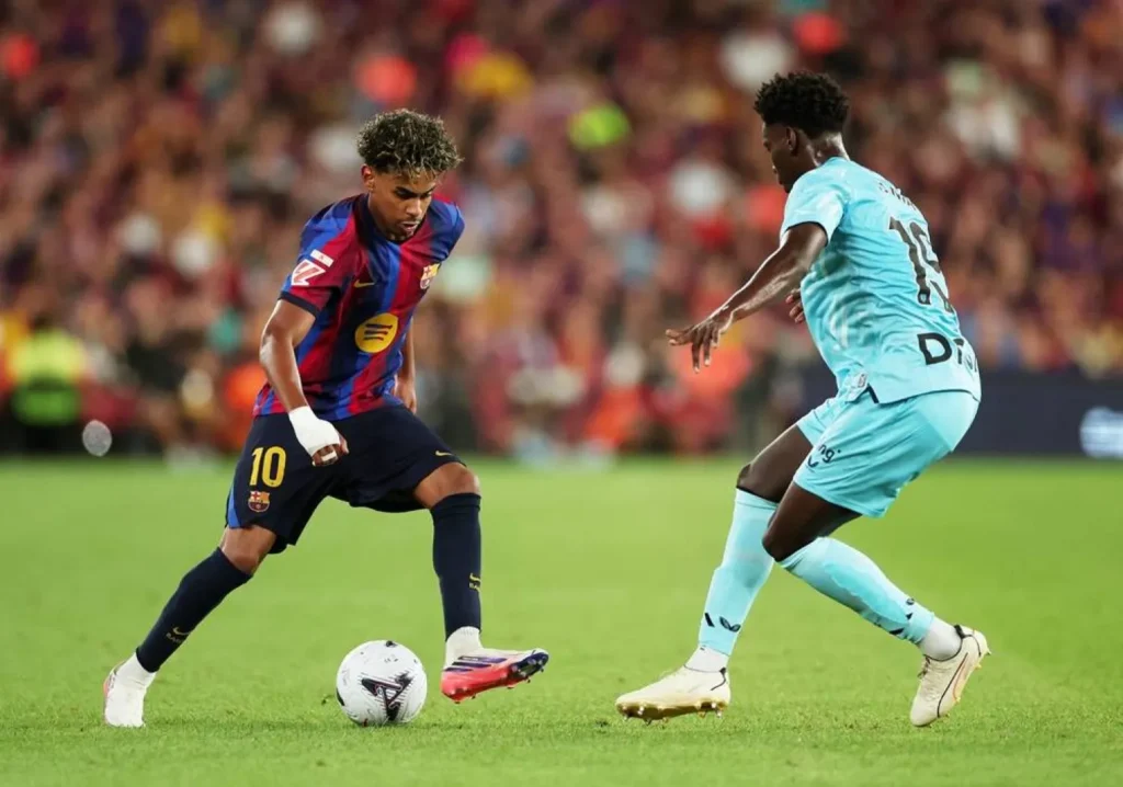 Lamine Yamal dribbling a ball in a Barcelona shirt.