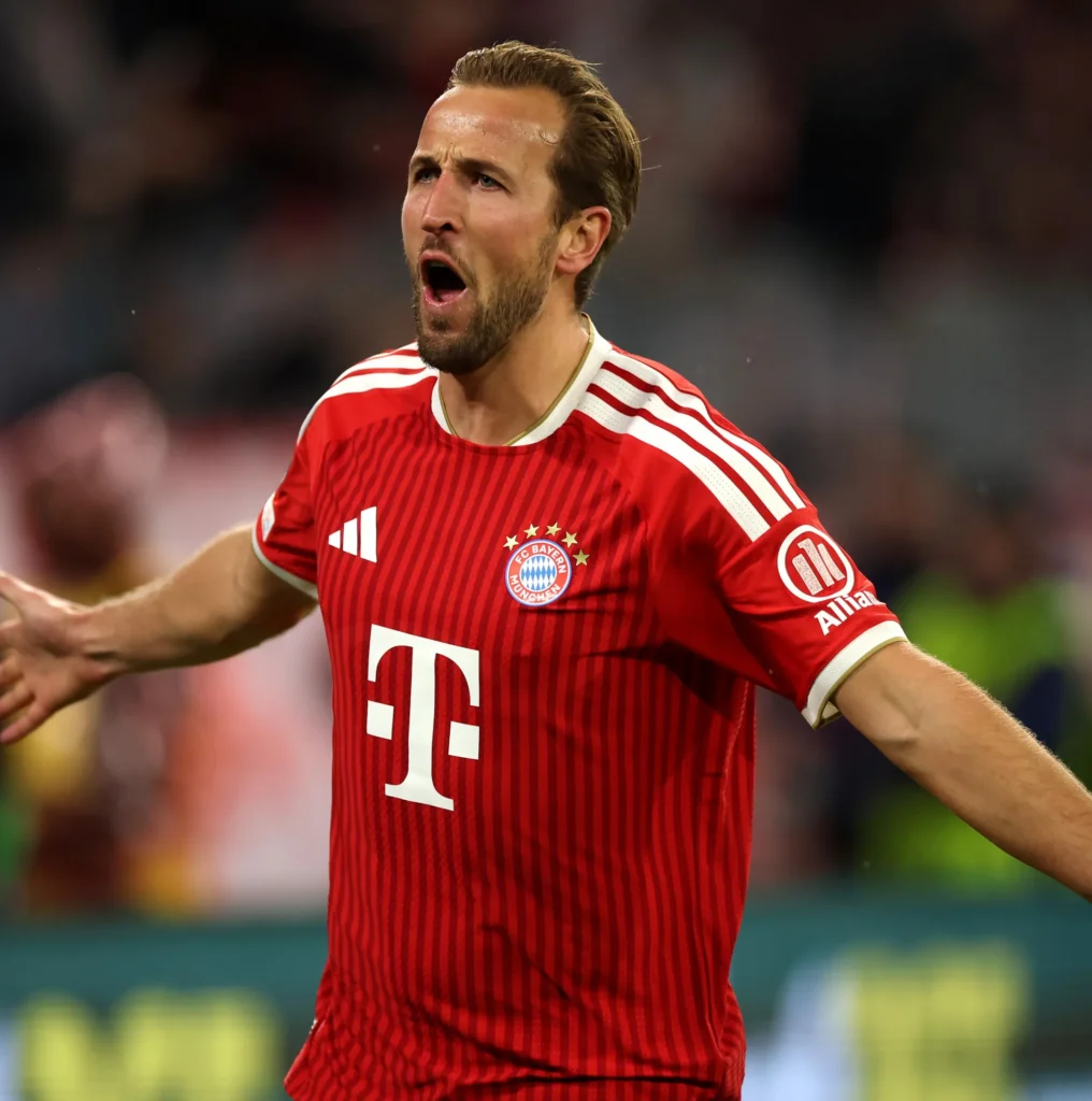 Harry Kane in a red Bayern Munich shirt on the pitch.