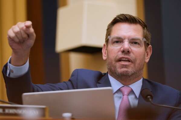 Eric Swalwell in a dark suit speaking at a news conference.