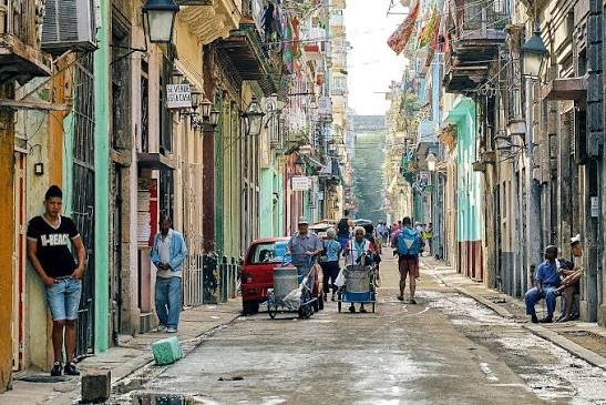 A street scene in Havana with old buildings and parked cars.