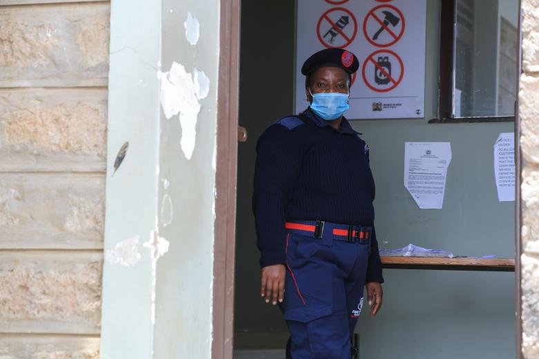 A person wearing a protective face mask stands outside a government building.
