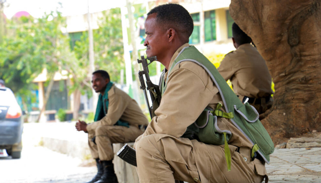 Armed fighters sit along a roadside in an African city.