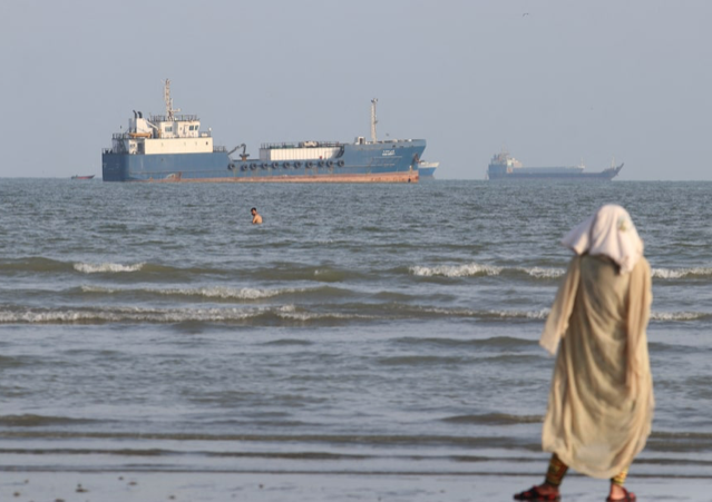 Tankers and cargo ships at sea in a narrow strait.