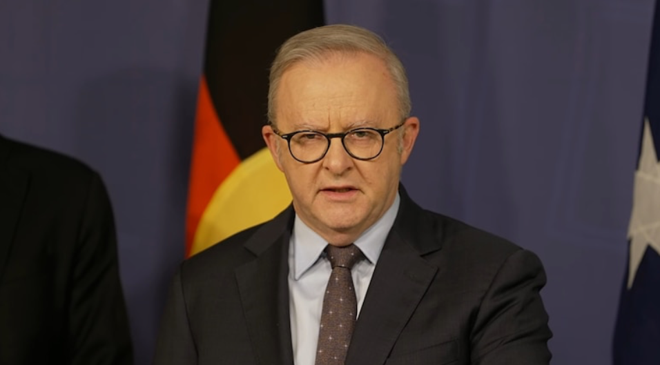 Anthony Albanese in a dark suit speaking at a podium.