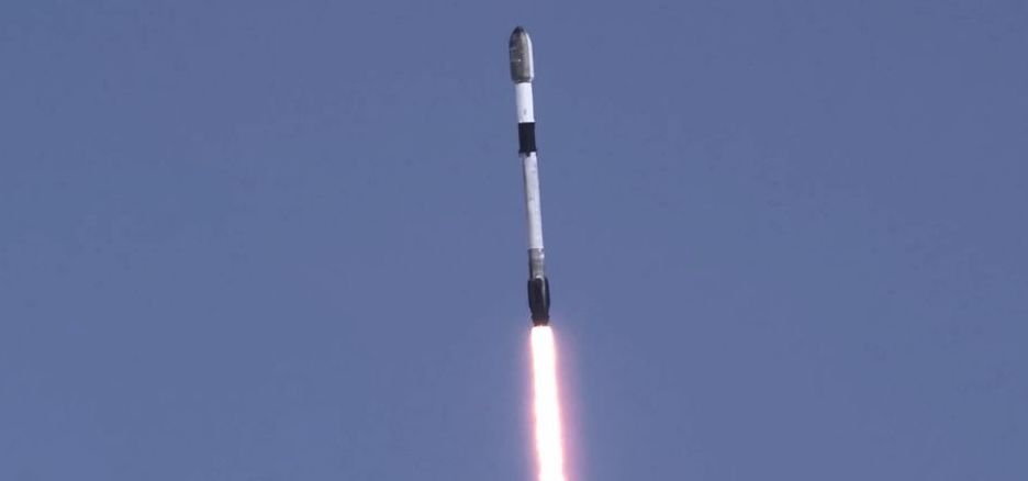A rocket rises into a dark sky on a trail of flame.