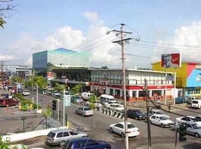 Commercial buildings and pedestrians along a busy street in central Chaguanas, Trinidad and Tobago.