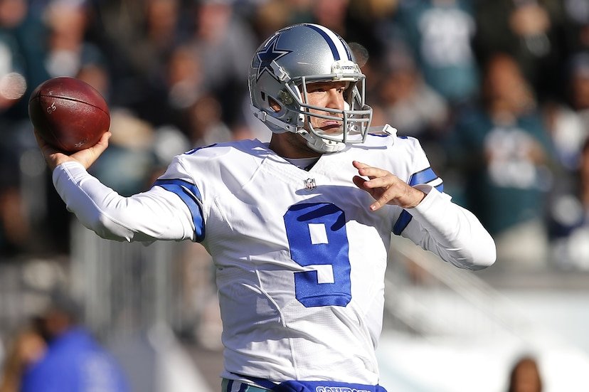 A football quarterback in a Dallas Cowboys uniform prepares to throw during a game.