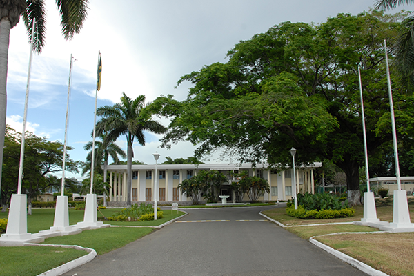The exterior of Jamaica House, a white government building, with a flag in front.