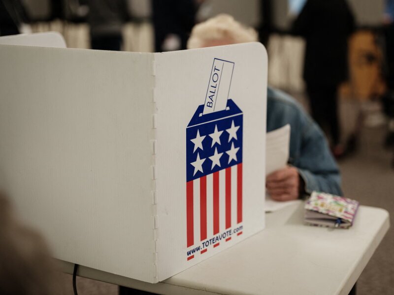 A person marking a paper ballot inside a privacy booth at a polling site.